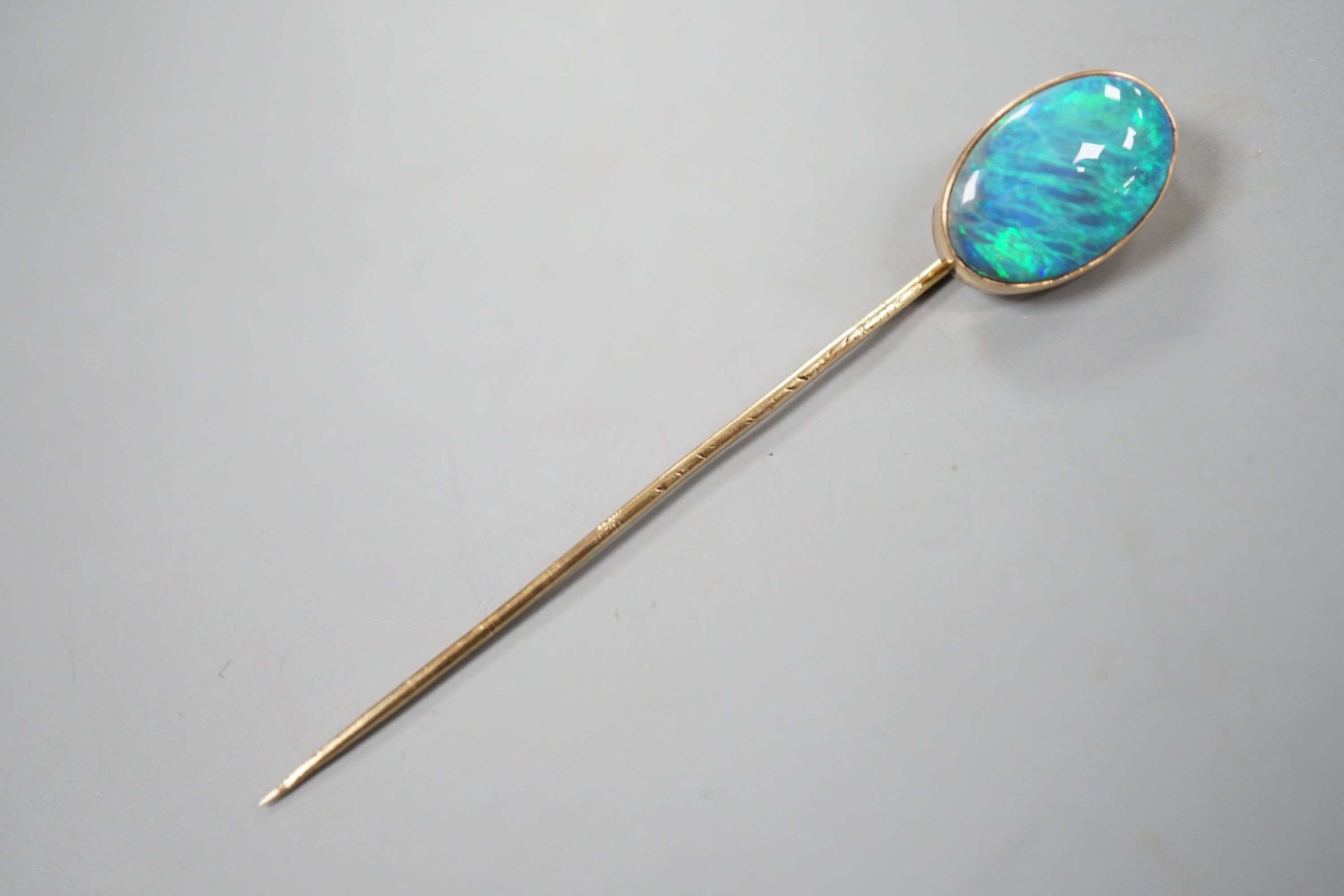 An Edwardian yellow metal and oval black opal set stick pin, 67mm, gross 2.7 grams